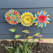Colorful flower-shaped garden stakes against blue siding.