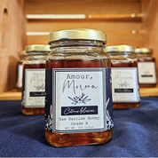 Jar of raw Haitian honey on a blue cloth with wooden shelves in the background.