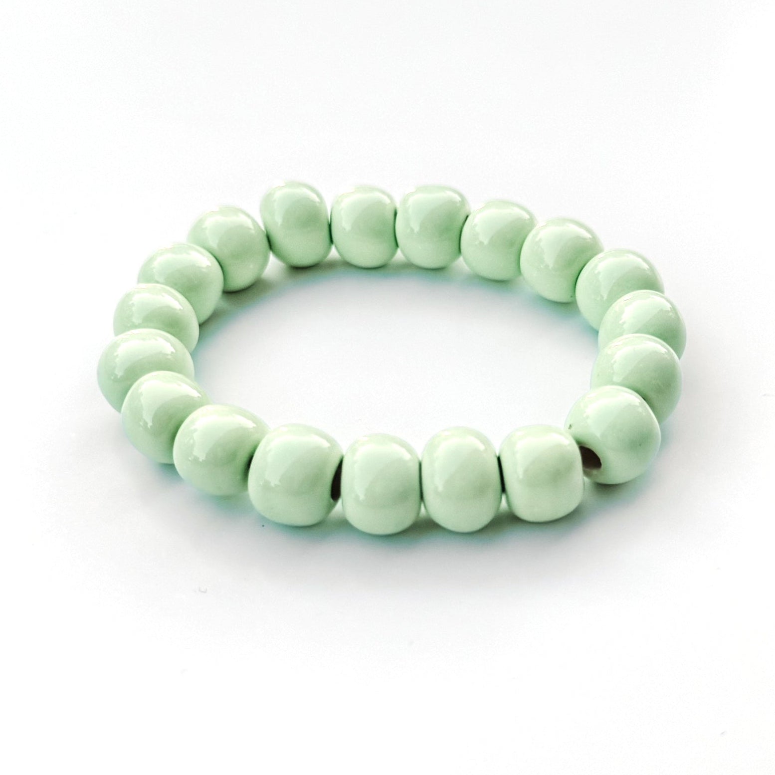 A beaded stretch bracelet made of glossy, rounded pale mint green beads, displayed on a clean white background.
