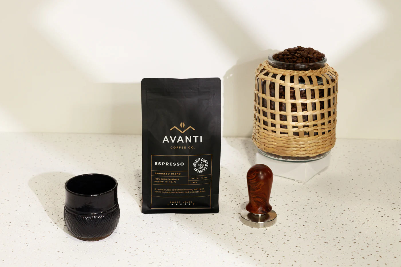 Avanti coffee package with a wooden tamp and glass container on a white surface