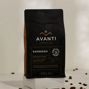 Avanti Coffee Co. Espresso coffee bag with scattered coffee beans on a light background