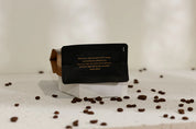 Bottom of coffee bag with text on a white surface with scattered coffee beans