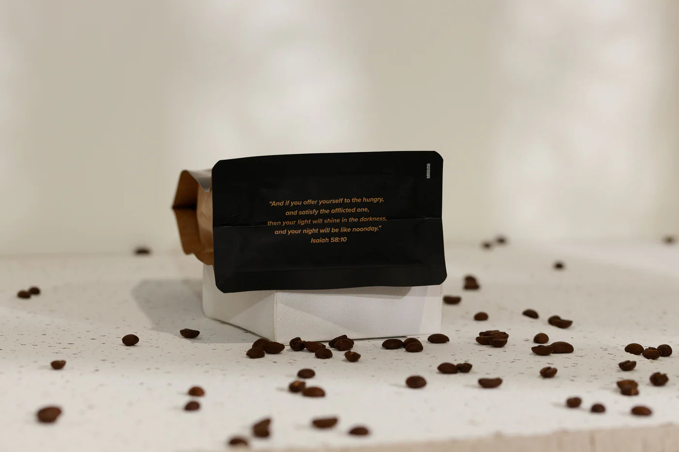 Bottom of coffee bag with text on a white surface with scattered coffee beans