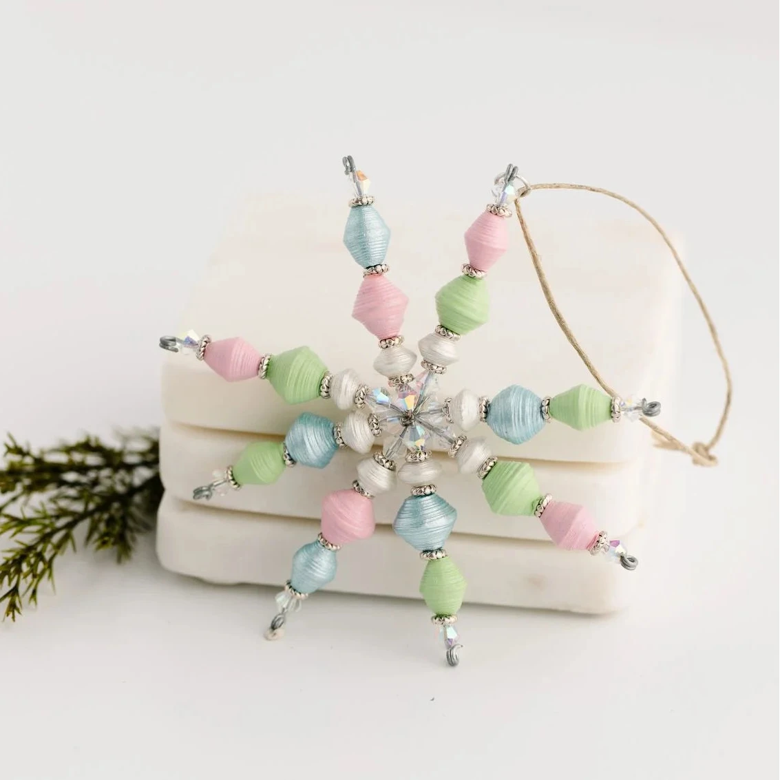 Decorative snowflake ornament with pastel beads on a white surface